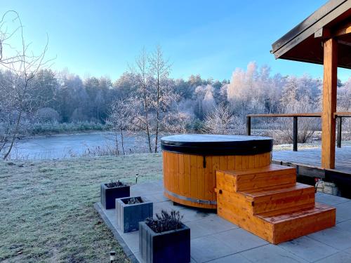 a wooden barrel sitting on a patio next to a river at 2os Domek z prywatną balią z jacuzzi, kominek, na odludziu, jedyny na 10000 m2 terenie, widok na las, lubelskie Roztocze in Oseredek