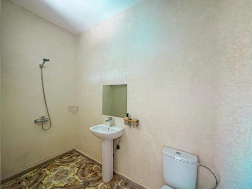 a bathroom with a sink and a toilet and a mirror at Évasion Douce avec jardin, terrasse et piscine privée in El Aggada