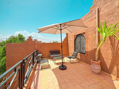 a patio with two chairs and an umbrella at Évasion Douce avec jardin, terrasse et piscine privée in El Aggada