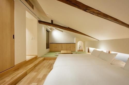 a bedroom with a large white bed in a room at Enso Machiya in Kyoto