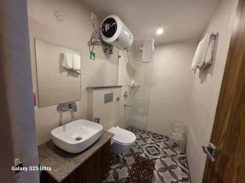 a bathroom with a sink and a toilet and a mirror at Hotel Shiva Yog Sthal in Rishīkesh