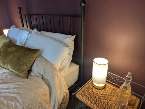 a bed with a lamp and a bottle on a table at Compton House, Llanfyllin in Llanfyllin