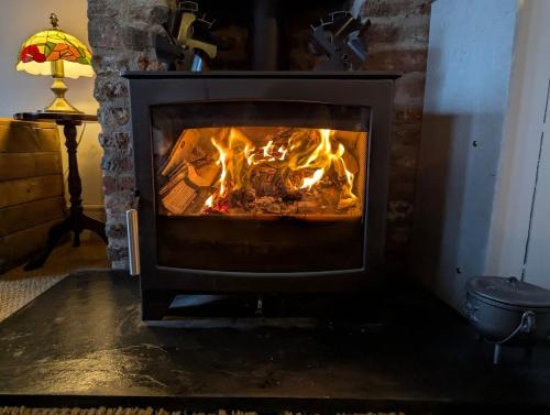a fireplace with fire in it in a living room at Compton House, Llanfyllin in Llanfyllin