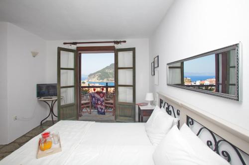 a bedroom with a bed and a view of the ocean at Aperanto Galazio in Skopelos Town