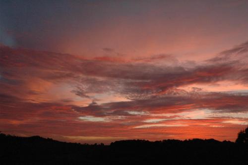 a sunset with a red in the sky at La Grange - Gite Mur de Barrez in Mur-de-Barrez