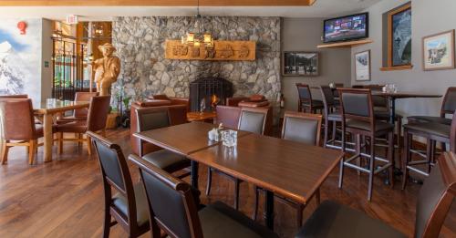 a restaurant with tables and chairs and a fireplace at Coast Hillcrest Hotel in Revelstoke