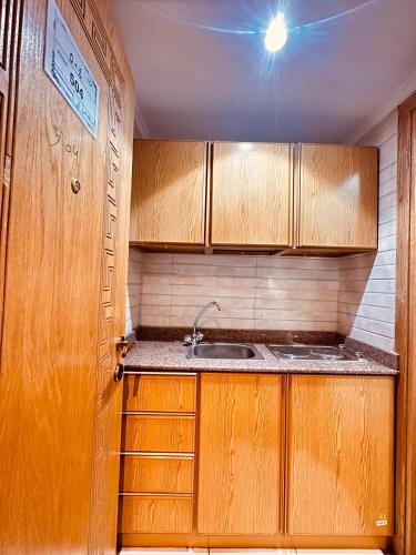 a small kitchen with wooden cabinets and a sink at فندق غزالة برفكت توصيل مجاني للحرم - Ghazala Perfect Hotel Free shuttle service to the Haram in Makkah