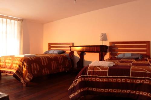 1 dormitorio con 2 camas y ventana en Emperatriz Guest House, en Cusco