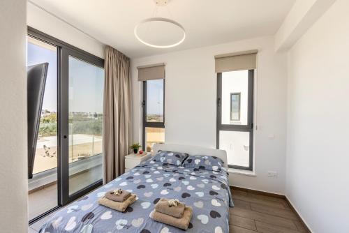 a bedroom with a bed and large windows at Seaside Emerald in Paralimni