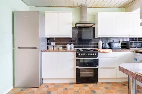 a white kitchen with white cabinets and appliances at Beaconsfield House - Pleasant Area, Free Parking & Quiet Stay near LTN in Luton