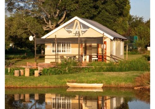a small house with a small boat in the water at Imbabali Retreat & Venue in Magaliesburg