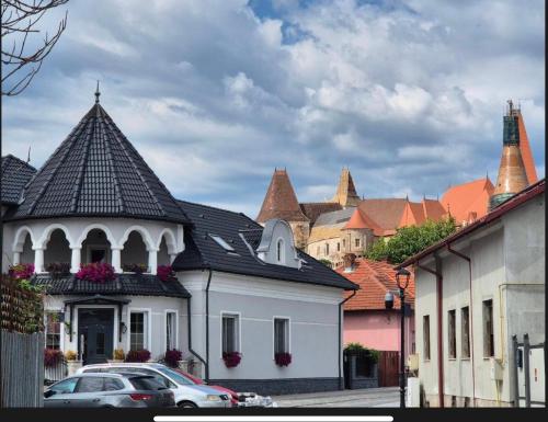 a white building with a black roof in a city at The Corner House in Hunedoara
