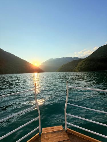a boat on a lake with the sun setting at Studio Apartman Gracia in Pluzine