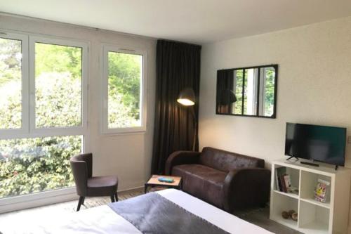 a bedroom with a bed and a couch and a television at Logis Latitude Ouest Hôtel Restaurant & Spa in Locronan