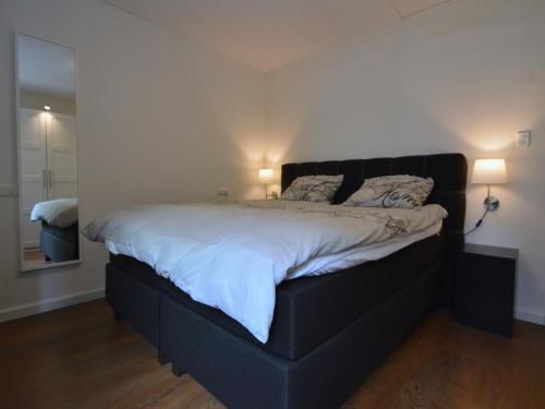 a bedroom with a large bed with a black headboard at Holiday Home Voorthuizen near De Veluwe in Voorthuizen