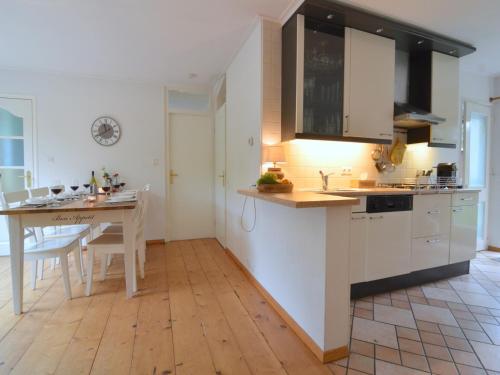 a kitchen with white cabinets and a wooden floor at Holiday Home Voorthuizen near De Veluwe in Voorthuizen