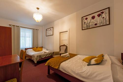 a room with two beds and a table and a desk at Pokoje Gościnne Tylice in Zgorzelec