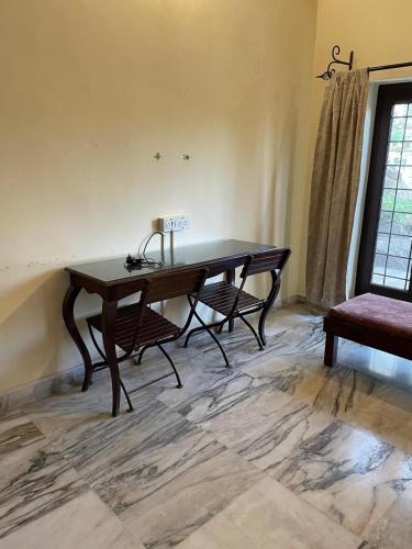 Habitación con escritorio de madera y 2 sillas. en Anandmai Heritage Villa Mount Abu, en Delmāra