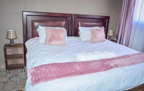a bed with pink and white sheets and pillows at Mountain Beauty in Mbabane