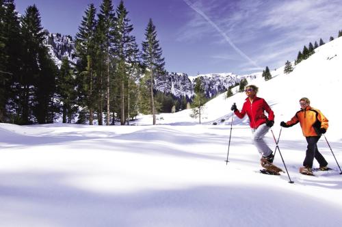 two people are skiing down a snow covered slope at Hotel Oberwirt - nahe an Saalbach und Zell am See, Viehhofen Sommercard in Viehhofen