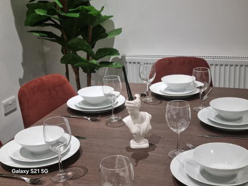 a table with plates and wine glasses on it at Cozy Riverside Apartment 5mins to train station in Gravesend