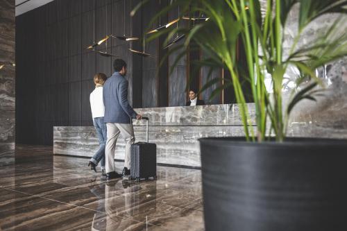 a man and woman walking through a lobby with their luggage at The Icon Limassol in Limassol
