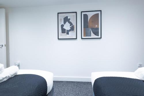 two beds in a room with three pictures on the wall at Cozy Riverside Apartment 5mins to train station in Gravesend