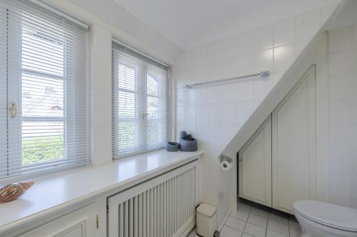 a white bathroom with a toilet and a window at Primera in Keitum