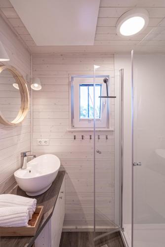 a white bathroom with a sink and a shower at Hausboot Schatzkiste in Fehmarn