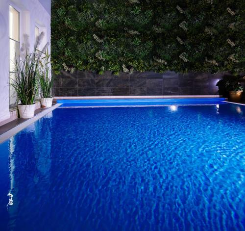 a large blue swimming pool with plants on the wall at Rathener Hof by STEIGER Hotels in Kurort Rathen