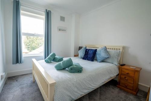 Un dormitorio con una cama con almohadas azules y una ventana. en Beachside Bliss!, en Pakefield