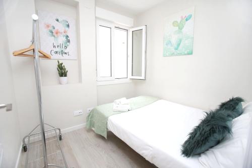 a white bedroom with a bed and a window at El Rincon de la Merced Terraza Aire acondicionado in Almazán
