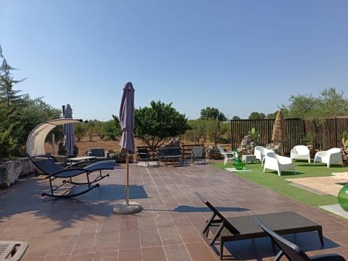 a patio with chairs and an umbrella and tables and chairs at Borgo Incanto in Acquaviva delle Fonti