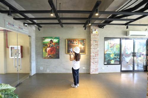 a woman taking a picture of a painting in a museum at Dream Golftel by Dream Residences in Manolo Fortich