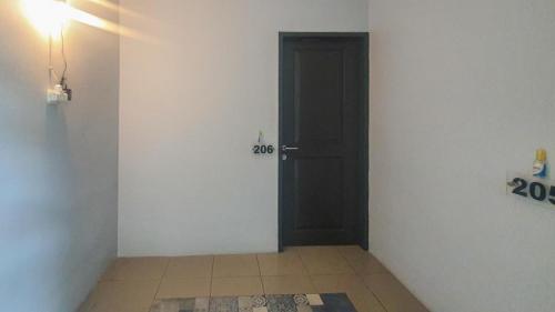 a hallway with a black door and a tile floor at Panorama Inn Residence Batu Redpartner in Batu