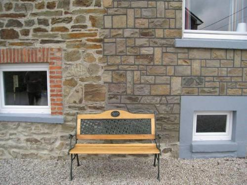 a wooden bench sitting in front of a stone building at Apartment in Halenfeld-Amel with Terrace in Amblève