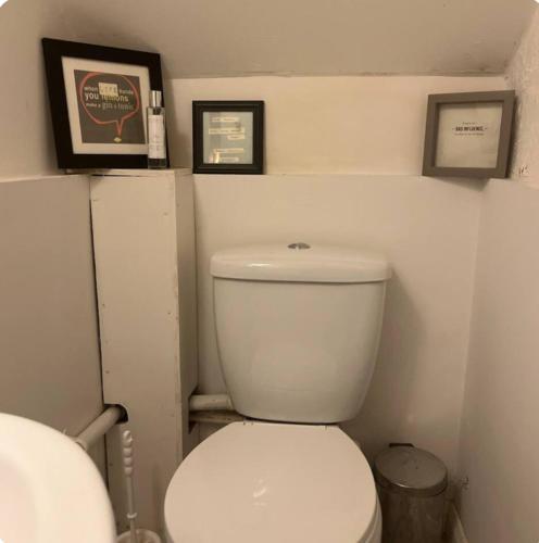 a bathroom with a toilet with two pictures on the wall at Northmill Cottage - Charming 2 bed residential property with courtyard in Midhurst
