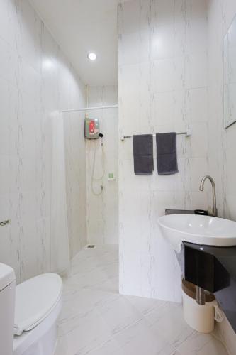 a white bathroom with a toilet and a sink at StayKa Suites in Karon Beach