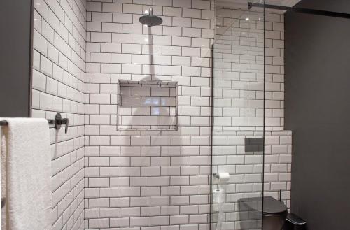 a white tiled bathroom with a shower and a toilet at Haisley Hotel in Hilton