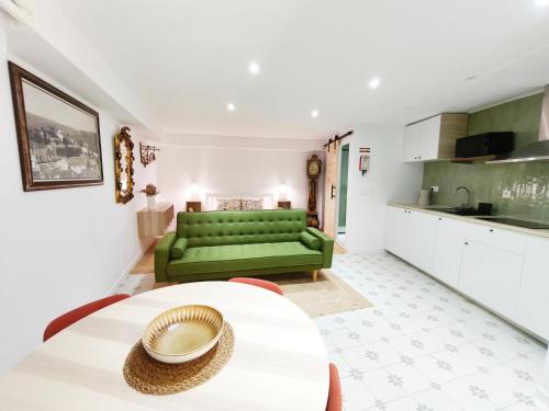 a living room with a green couch and a table at Retiro da Igreja by Casas do Planalto in Torre de Moncorvo