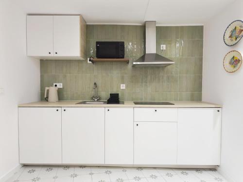 a kitchen with white cabinets and a sink at Retiro da Igreja by Casas do Planalto in Torre de Moncorvo