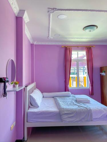 a bedroom with purple walls and a bed with a mirror at The Nice Pool Villa Sittahip เดอะไนท์พูลวิลล่าสัตหีบ in Ban Tao Than