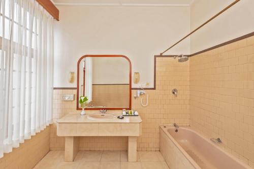 a bathroom with a sink and a tub and a mirror at The Grand Hotel - Heritage Grand in Nuwara Eliya