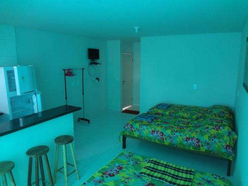 a bedroom with a bed and a kitchen with stools at Flat Paraty Studio in Paraty