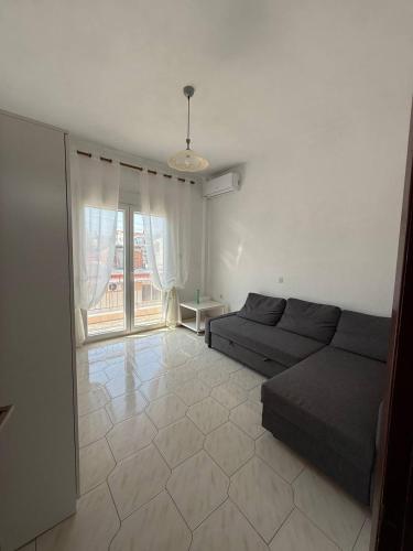 a living room with a couch and a large window at Alex Apartment in Nea Fokea