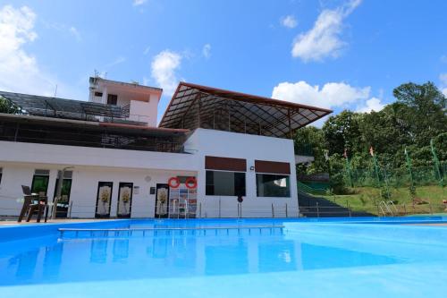 a villa with a swimming pool in front of a building at Tapovan Happiness Valley in Kollam