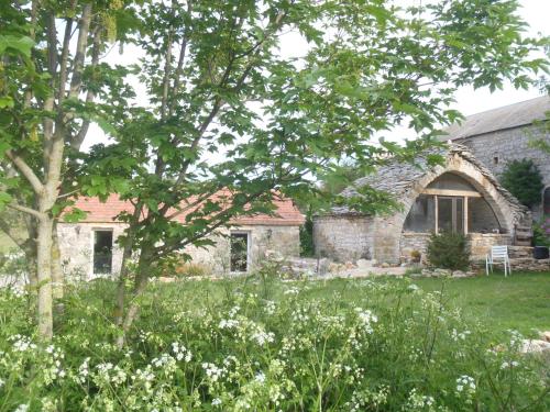 an old stone house with a tree in the yard at chambres du Domaine de Bombes in Mostuéjouls