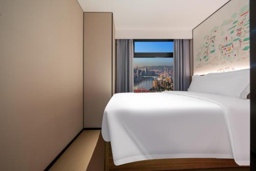 a bedroom with a white bed and a window at Chongqing Xingcheng Chengyijing Hotel Management Co., Ltd in Chongqing