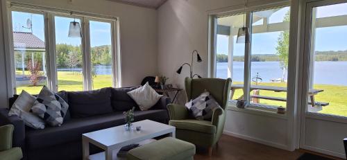 a living room with a couch and a table and windows at Lakeview Houses Sweden in Falun