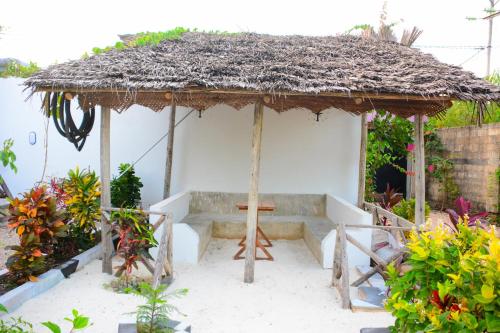 a small hut with a bench and a cross in it at Sailors Villa in Jambiani